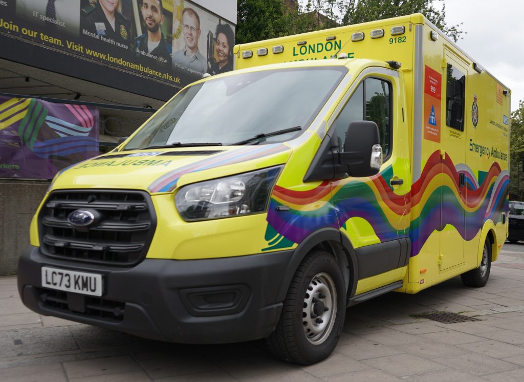 Picture of a London Ambulance with the Pride flag decorated on the front and side.