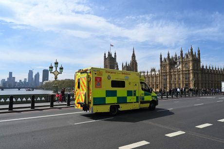 London Ambulance Service vehicle crossing bridge next to Houses of Parliament