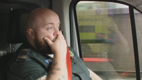 Ambulance clinician looking shocked at something they've heard on their radio. 