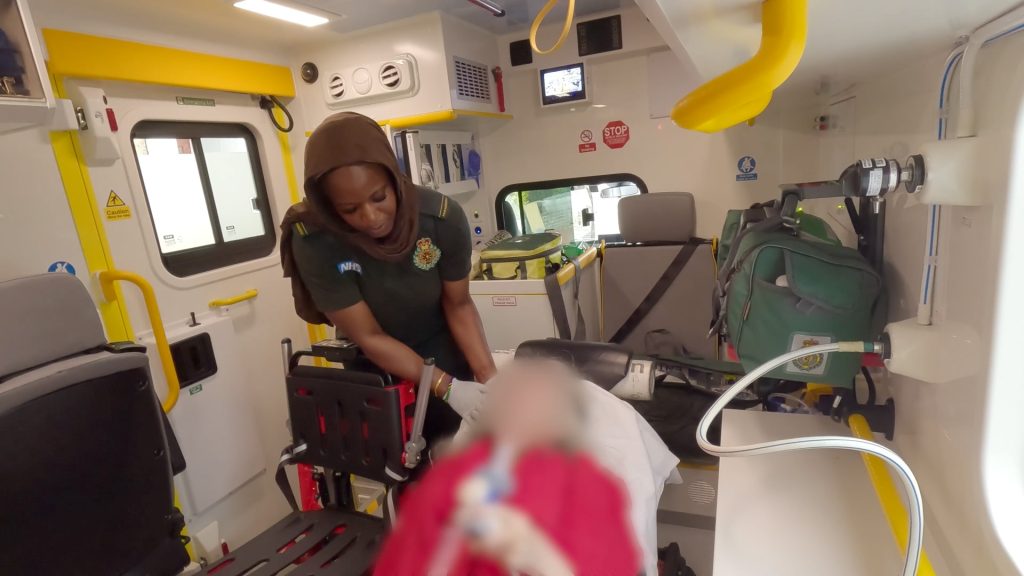 Himnah caring for a patient inside the back of an ambulance.