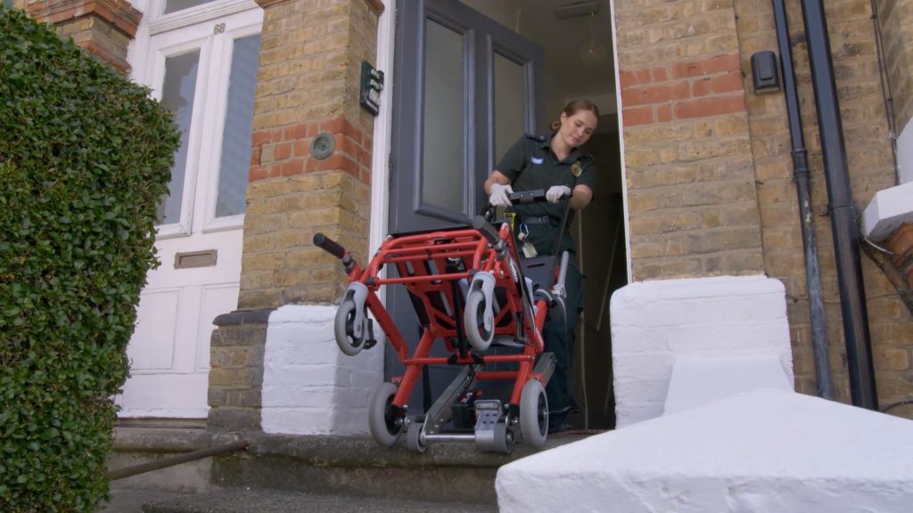 Clinician wheeling a chair into a patients home. 